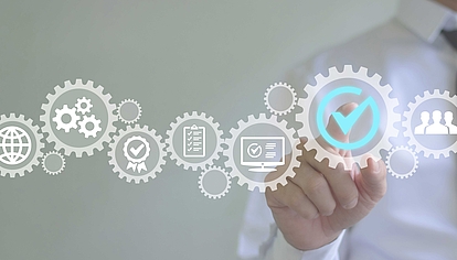 Hand pointing at digital gear with check mark – symbolizes quality control, efficiency, and digital processes