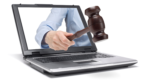 Procurement Support – Efficient Tendering & Vendor Selection A judge’s gavel emerging from a laptop screen, symbolizing LS telcom’s procurement support services, including tender preparation, bid evaluation, and vendor selection.